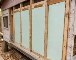 A backyard chicken coop with rigid foam board insulation installed in the wall framing before the siding goes back on
